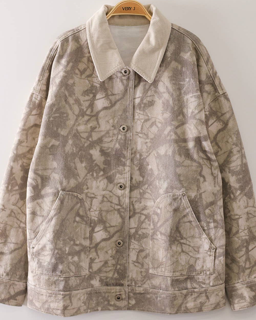 Women's camo jacket in a taupe and cream branch print with a cream corduroy collar, front view on a hanger