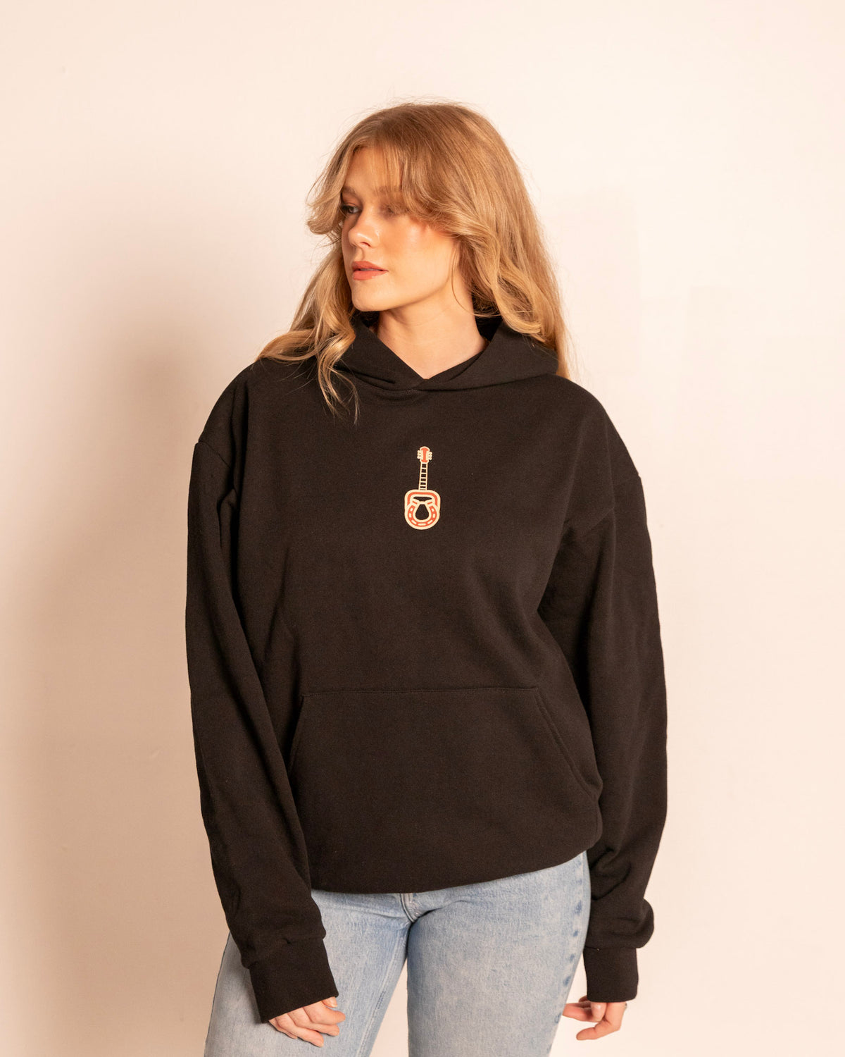 Broadway Hoodie in faded black on model, front view with the guitar and horseshoe chest print