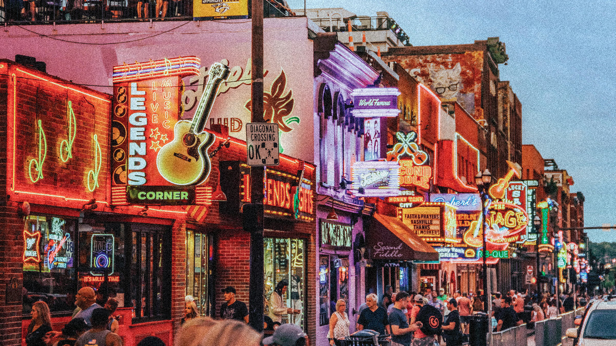 Neon signs lit up along Lower Broadway in Nashville, including Legends Corner