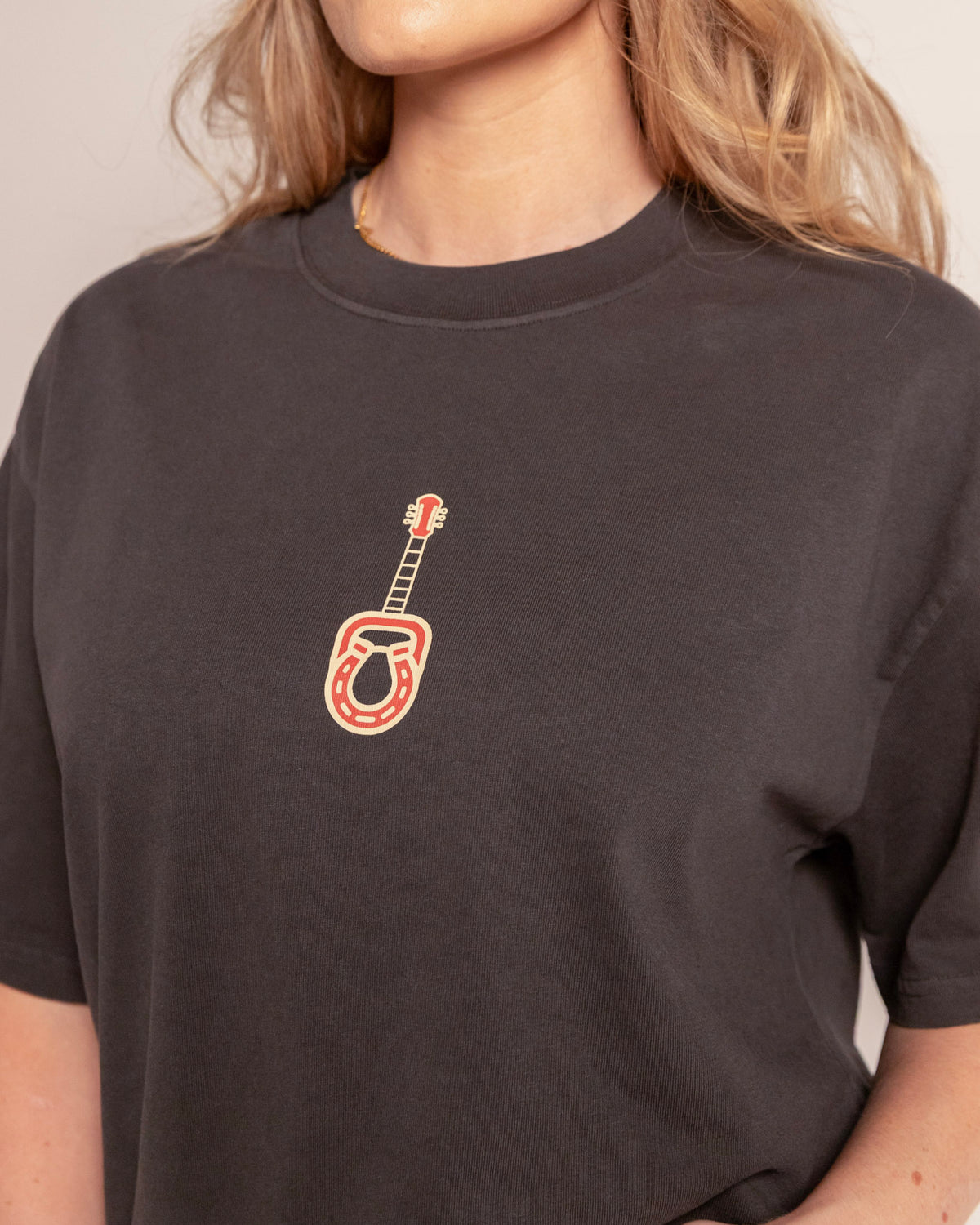 Broadway Tee in faded coal, close-up of the guitar and horseshoe chest print