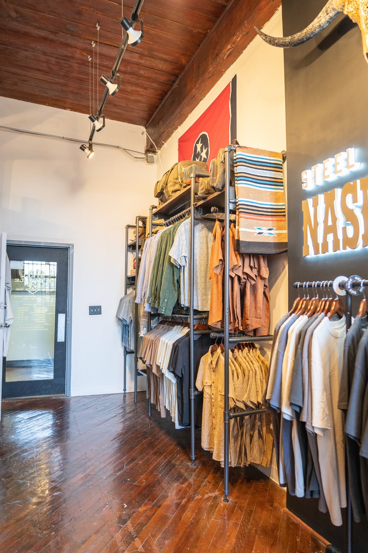Racks of western shirts and jackets under a wood plank ceiling at Steel & Saddle in Marathon Village, Nashville