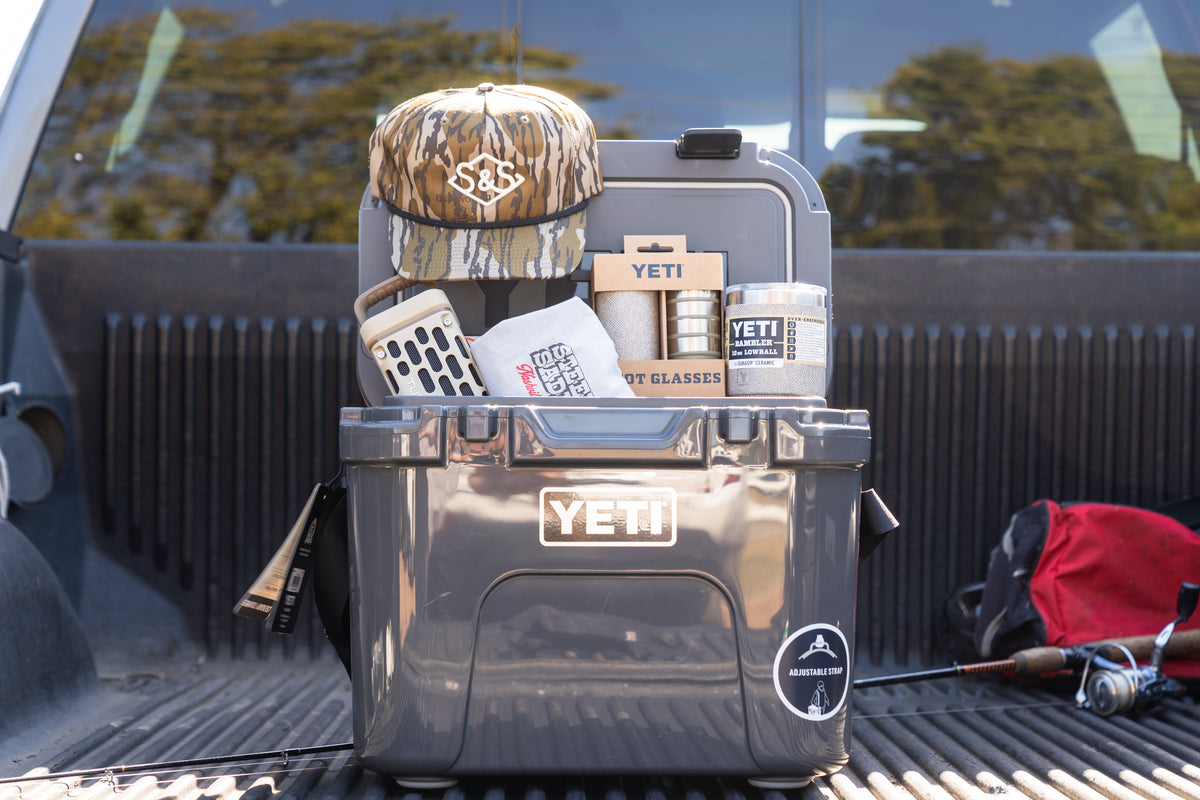 Giveaway prizes in a truck bed: YETI cooler, YETI drinkware and a camo Steel & Saddle cap