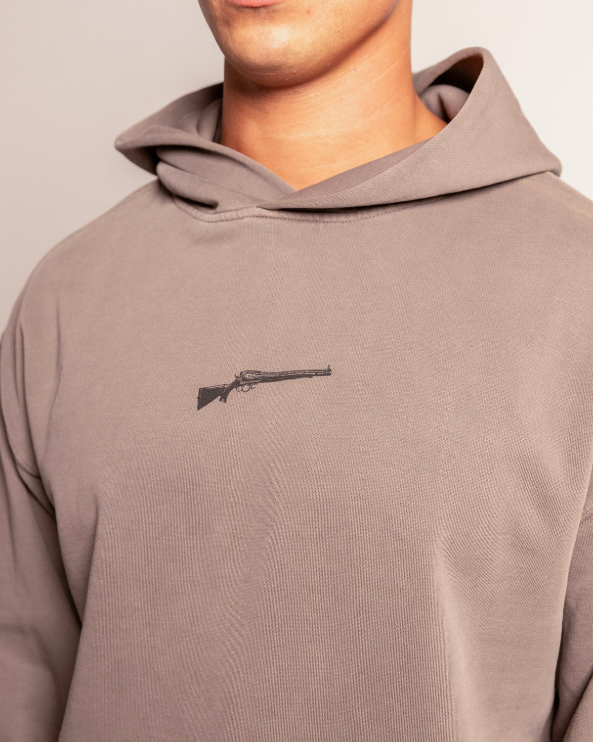 Lever Action Hoodie in faded grey on model, close-up of the lever action rifle chest print