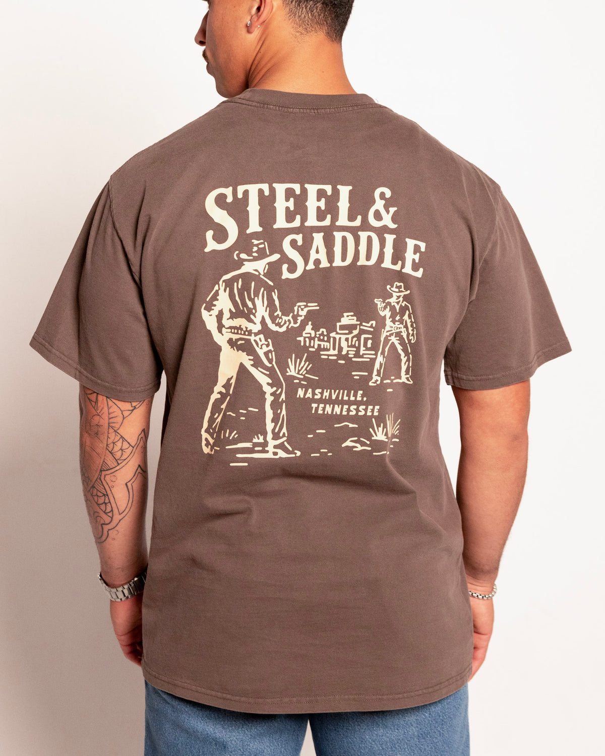 Standoff Tee in faded brown on model, back view with the two gunslingers facing off on an old western town street